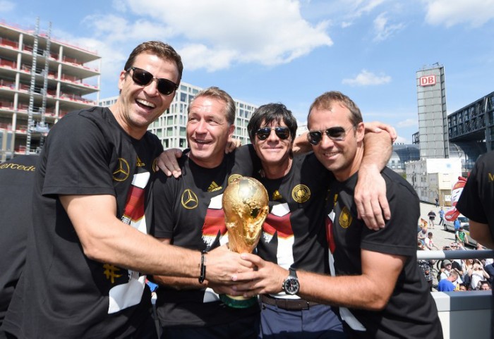 Teammanager Oliver Bierhoff, Torwarttrainer Andreas Koepke, Bundestrainer Joachim Loew und AssistenztrainerHansi Flick feiern am 15.Juli 2014 den WM-Titel in Berlin am Brandenburger Tor. AFP PHOTO / POOL/ MARKUS GILLIAR